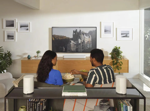 Couple enjoying music with Era 100 SL Dope Compact Microphone Free Wireless Speaker With WiFi Bluetooth in living room setup.