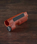 TL Racker 1000 Lumen 20000 Candela Tactical Forend Light with Ambidextrous Controls for Remington 870 in orange on table