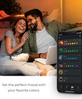Couple in a cozy living room setting with phone app controlling No Hub Smart LED Bulb With Multicolor Spiral Filament WiFi Connected.
