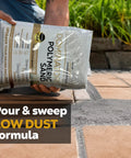 Person pouring Titanium Gray Heavy Duty Polymeric Sand For Patio Paver Joints And Stone Gaps Featuring Ceramic Flex Technology Killer Stability No Sweat Setup 10 Pound Bag onto paver joints.