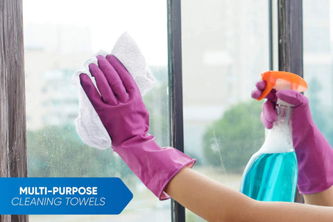 Person cleaning a window with a pack of 50 white 12 by 12 inch cotton terry cleaning cloths for auto detailing and general cleaning.