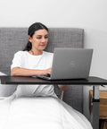 Woman using a Rolling Overbed Table With Wheels For Bedside, Sofa Or Recliner Adjustable Height Laptop Desk in bed