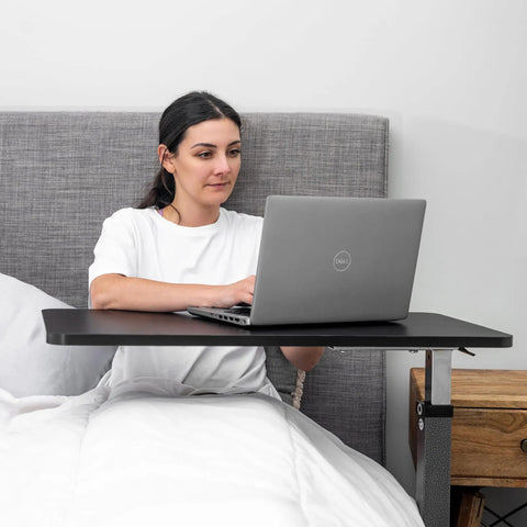 Woman using a Rolling Overbed Table With Wheels For Bedside, Sofa Or Recliner Adjustable Height Laptop Desk in bed