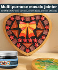 Heart-shaped mosaic with colorful tiles using Mosaic Grout For Crafts Black 400g Quick Dry Crystal Tile Grout, jar in foreground.