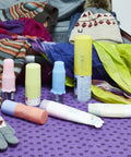 Silicone Bottle Covers 10 Pack for Travel Size Toiletries on purple cloth with winter clothing and scarves in background