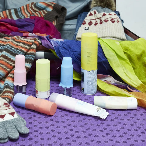 Silicone Bottle Covers 10 Pack for Travel Size Toiletries on purple cloth with winter clothing and scarves in background