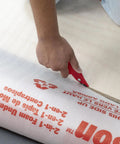 Person cutting Top Shelf 100 Square Foot Laminate And Engineered Wood Flooring Underlayment Roll with a utility knife.