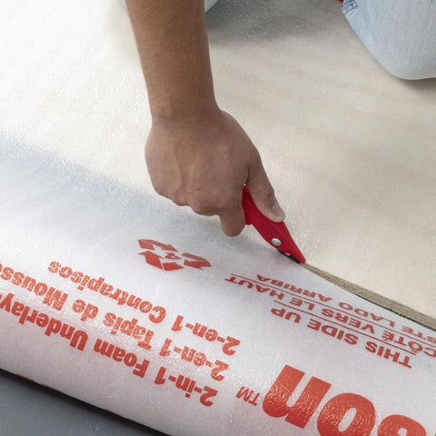 Person cutting Top Shelf 100 Square Foot Laminate And Engineered Wood Flooring Underlayment Roll with a utility knife.