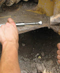 Close-up of Grease Joint Rejuvenator Kit in use on heavy equipment; silver shaft tool near a joint.