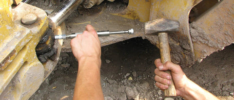 Close-up of Grease Joint Rejuvenator Kit in use on heavy equipment; silver shaft tool near a joint.