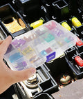 Hand holding 100 Piece Car Fuse Assortment Kit With Tester And Puller For Trucks SUVs Boats And Automotive Electrical Repair Tools Includes Low Profile Mini Fuses And Durable Portable Carry Case For Quick On The Go Electrical Fixes over an open fuse box