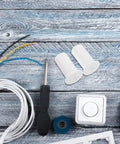 Get These Cool Silicone Wall Hole Plugs To Block Dirt And Water! Perfect 4 Pack For 25mm Cables Makes Home Improvement Super Easy With Gray And White Look. White silicone wall hole plugs with cables, screwdriver, and outlet cover on wood surface