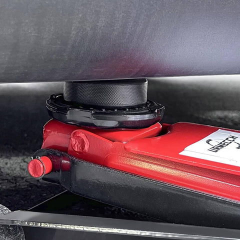 Tesla Jack Pad Set 4 Pack Rubber Lifting Pucks For Model 3 Y S X installed on a car chassis with a red heavy-duty jack