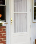 Tough As Nails Brass Storm And Screen Door Handle Set With Solid Lock And Key featuring a reversible latch on a white door.