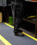 Person standing on Diamond Plate Select UltraSoft Anti Fatigue Floor Mat 4 Ft By 2 Ft 15 16th Inch Thick Black With Yellow Edge