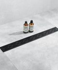24 Inch Rectangular Matte Black Shower Drain With Removable Brickwork Pattern Grate Brushed 304 Stainless Steel Floor Drain Includes Adjustable Leveling Feet And Hair Strainer For No Fuss Install installed in bathroom floor showing black grate