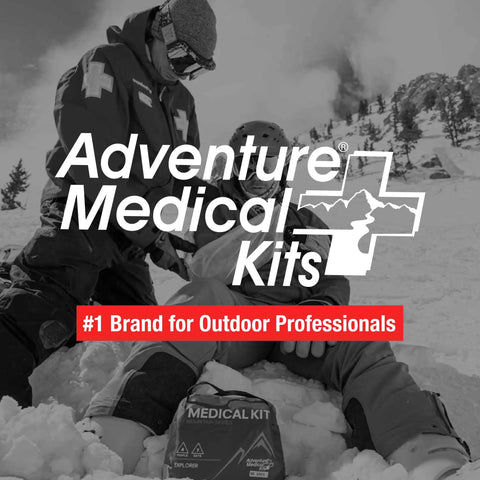 Mountain Series Explorer Outdoor Expedition Grade Emergency First Aid Kit in snow with adventurers in background.