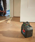 Green Beam Self Leveling 360 Degree Cross Line Laser in use for floor alignment on job site with visible guiding laser.