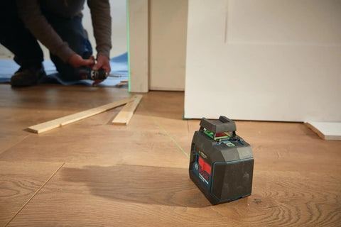 Green Beam Self Leveling 360 Degree Cross Line Laser in use for floor alignment on job site with visible guiding laser.