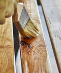 Applying Top Shelf 100 Percent Pure Linseed Oil Wood Finish And Protective Sealer For Indoor Outdoor Furniture Plus Hardwood Surfaces Deeply Absorbs To Beat Sun And Rain Wear Keeping Grains Smooth And Radiant 32 Ounce Can to a wooden surface.