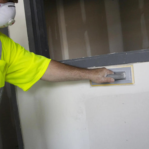 Person using Quick Change Hook And Loop Pro Grade Drywall Sandpaper 80 And 100 Grit Sheets 4.5 X 10.5 Inches on wall