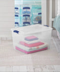 Blue 66 Quart Clear Storage Bin with Latching Lid for Easy Grip Heavy Loads stackable with colorful stacked clothing inside.