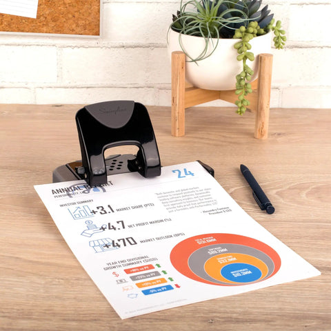 Built Different Two Hole Punch Crushes Twenty Sheets Like Nothing Else With Smart Touch Low Effort Grip And Tight Accuracy Alignment Track For Quick Paper Organizing Jobs In Sleek Black Gray on desk with report.