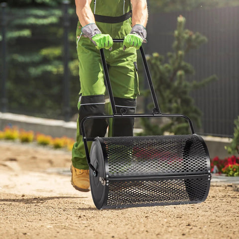 Person using 24 Inch Lawn Roller And Compost Spreader With Double Side Latches And Steel Mesh Basket For Top Dressing And Seedling Versatile Lawn Care Tool For Garden Farm Or Park Black Finish on soil