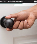 Hand gripping Black Matte Ball Style Passage Door Knob on white interior door, non locking, for closets and pantries.