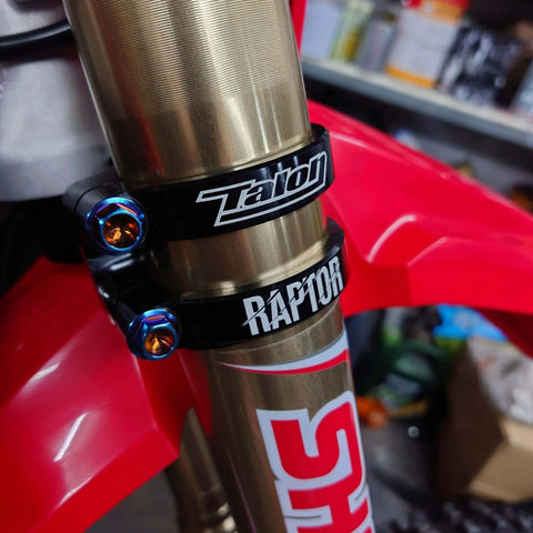 Close-up of motorcycle fork with burnt blue titanium flanged hex head bolts M6 x 1.0 x 25mm installed on black clamps.