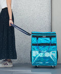 Person pulling Glitter Blue Rolling Grocery Tote With Wheels And Zipper Covered 8 Pocket Organizer on sidewalk