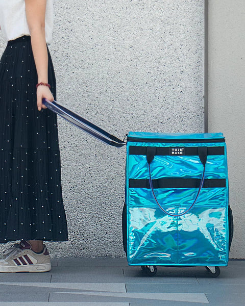 Person pulling Glitter Blue Rolling Grocery Tote With Wheels And Zipper Covered 8 Pocket Organizer on sidewalk
