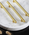 Ten Pack Gold Knurled Cabinet Pulls With 5 Inch Hole Centers 7 Inch Overall Length Brushed Brass Handles on marble surface.