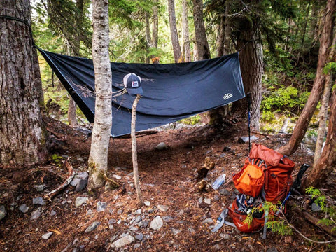 Waterproof Hammock Rain Fly Hex Tarp 12 by 9 Feet portable camping setup in forest with backpack and hat