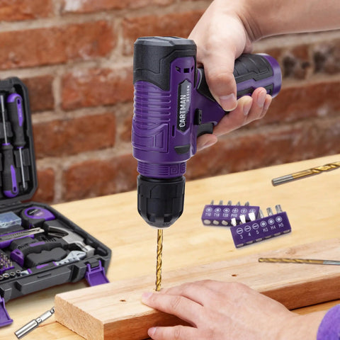 Person using 150 Piece Household Tool Set With 8V Cordless Drill Driver Kit For Home Maintenance DIY Projects And Repairs Complete Hand Tool Kit In Purple With Rust Resistant Tools And Handy LED Indicator Lights on wood