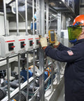 Engineer using Beefed Up Pro Grade Industrial Digital Multimeter For Troubleshooting With 1000 Volt AC DC Range in control room.