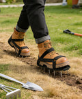 Person wearing Universal Fit Lawn Aerator Shoes With Two Inch Spikes And Adjustable Straps on grass, shovel in foreground.
