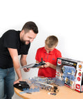 Father and son building the Build Your Own Visible Model Engine Kit With Four Cylinder Internal Combustion Mechanics, Realistic Sounds And Illumination, 100 Plus Pieces, STEM And Physics Based Replica Toy For Education And Hands On Fun on a table
