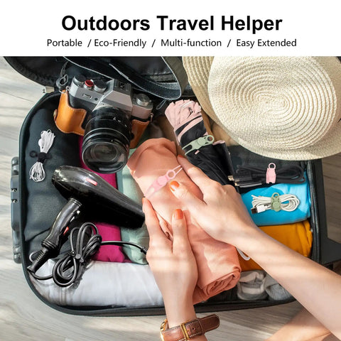 Open suitcase with packed clothes, camera, and a hairdryer, secured with silicone cable ties for travel organization.