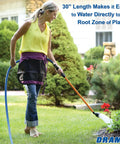 Woman using One Touch Rain Wand 30 Inch Garden Watering Wand with thumb control in garden for soft watering, focus on red flowers