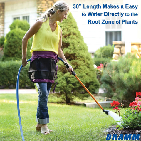 Woman using One Touch Rain Wand 30 Inch Garden Watering Wand with thumb control in garden for soft watering, focus on red flowers