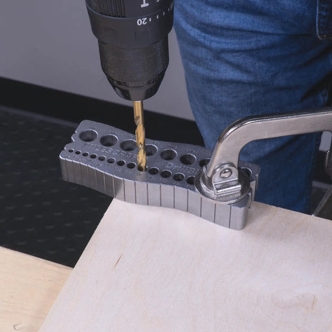 All Metal Handheld Drill Guide For Straight Holes With Twenty Five Drill Guides In One One Eighth To One Half Inch In Sixty Fourth Inch Increments Dual V Groove Design For Round Stock And Corners Ideal For Diyers And Woodworkers being used on wood.