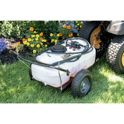 Tow-Behind Garden Sprayer With 15 Gallon Tank, 30 Inch Boom, 1.6 GPM At 100 PSI on grass beside flowers and tractor