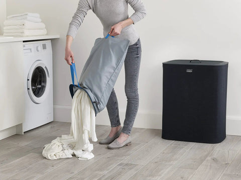 Person emptying Tota 90 Liter Laundry Hamper with Dual Compartment Separation and Lid, showing removable wash bag.