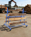Straight Up Heavy Duty Five Tier Lumber Rack, Mobile Cantilever Pipe Shelf With Rolling Brakes, Badass 500 Pound Capacity Garage Workshop Shed Steel Conduit Organizer Blue Finish Storage Cart holding logs outdoors.