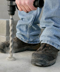 Worker using Fixed-Depth Bit MDPL050DIA For Three Eighths Inch Drop-In Anchors on concrete, ensuring precise depth control.