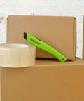 Westcott safety ceramic utility knife in lime green resting on cardboard boxes with packing tape
