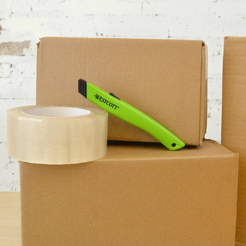 Westcott safety ceramic utility knife in lime green resting on cardboard boxes with packing tape
