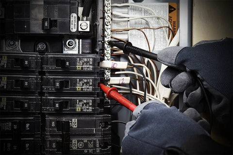 Hands using TL809 Electronic Test Lead Kit with probes on circuit breaker panel for maintenance