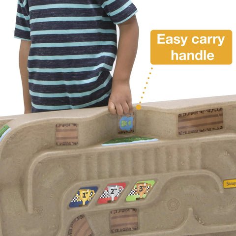 Child holding On The Go Kid Friendly Race Track Table With 2-Sided Play Surface For Cars And Trains, easy carry handle shown